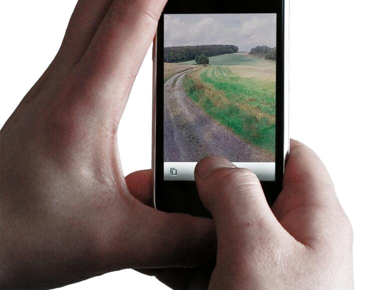 Die linke Hand hält das iPhone, mit dem Daumen der rechten Hand wird ausgelöst.