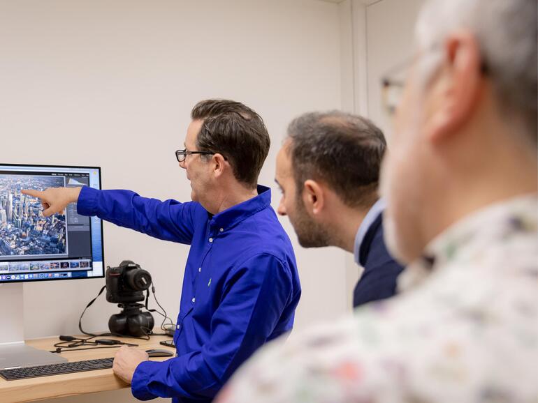 Jason Hawkes erklärt den eingeladenen Journalisten, wie er aus einem Helikopter heraus Städte fotografiert und wie ihm sein MacBook Pro bei dieser Aufgabe hilft.