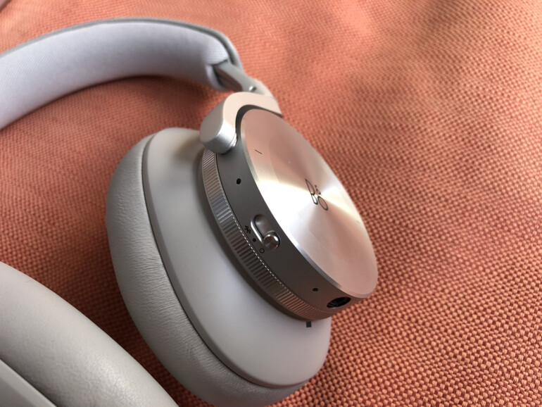 Der Drehregler auf der rechten Seite steuert die Lautstärke, der auf der linken die aktive Geräuschunterdrückung