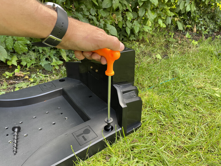 Die Ladestation wird mit großen Plastikschrauben im Rasen verankert.