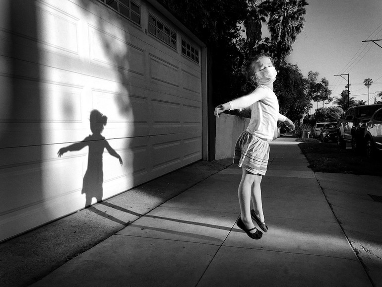 Der dritte Platz geht an Jeff Rayner aus Los Angeles für sein Foto &amp;quot;Side-Walking on Air,“ Shot on iPhone X. Ein Porträt eines jungen Mädchens, das schwerelos in einem Lichtpool auf dem Bürgersteig schwebt. 