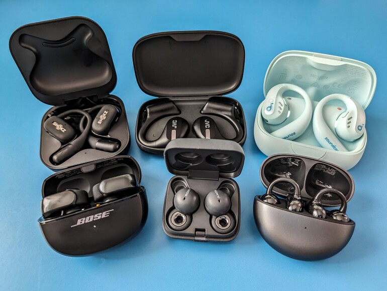 Sechs Open-Ear-Kopfhörer im Vergleich – im Uhrzeigersinn: Shokz Openfit, JVC Nearphones, Soundcore Aerofit Pro, Huawei Freeclip, Sony Linkbuds, Bose Ultra Open Earbuds.