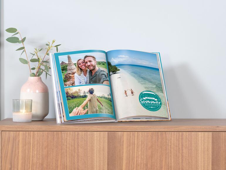 Aufgeschlagenes Pixum-Fotobuch auf einem Sideboard.