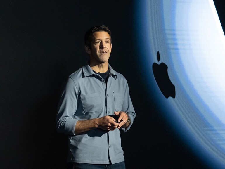 John Ternus bei einem Apple-Produktevent vor dem Apple-Logo.