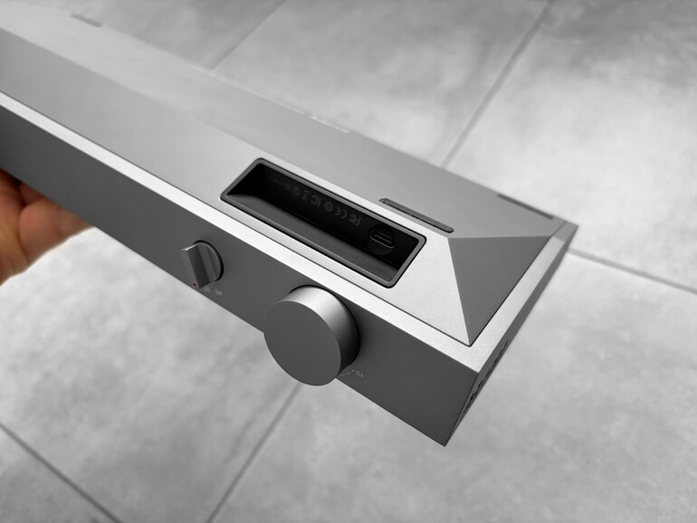 Der USB-C-Anschluss sitzt tief in einer Mulde, flankiert von den Prüfzeichen. Darüber der Umschalter für Kabel-, Funk- und Aus-Betrieb, rechts der große Lautstärkeregler.