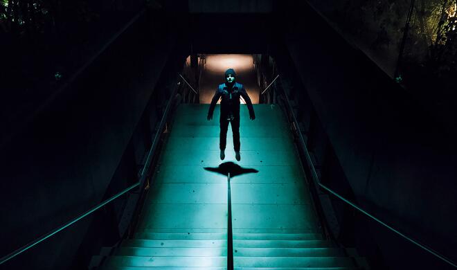 Mit dem iPhone 7 (Plus) aufgenommen: Man vor spärlich beleuchtetem Treppenaufgang mit Spiegelung an Wänden