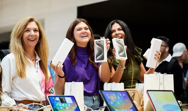 Kundinnen im Apple Store halten ihr neues iPhone in der Hand