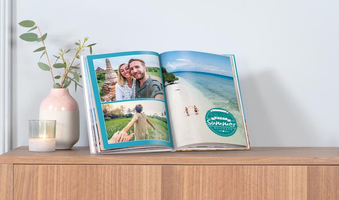 Aufgeschlagenes Pixum-Fotobuch auf einem Sideboard.