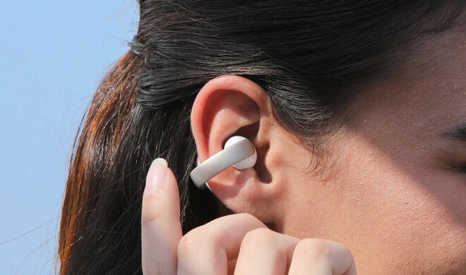 Wir ein Schmuckstück hängen die AeroClip von Soundcore am Ohr.