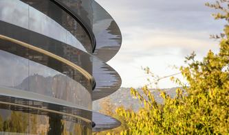 Gedankenverlorene Apple-Mitarbeiter laufen am Apple Campus vor Scheiben
